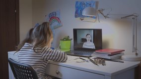 Caucasian girl is a preschooler, studying by watching a remote e-learning teacher on a laptop or a video call from a teacher on a webcam. Preparing students for school.