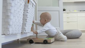 Baby sitting on the floor exploring new world around him touches everything, cute 7 month old baby boy playing with toys at home. High quality 4k footage