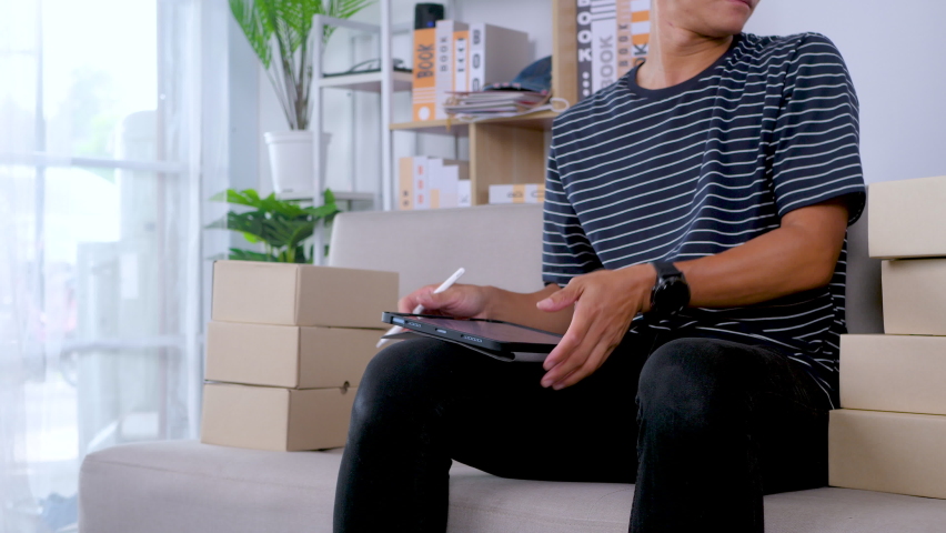 Startup on-line business entrepreneur SME, Man packing product in box and working with paperwork at home office. SME e-commerce telemarketing concept. 4K