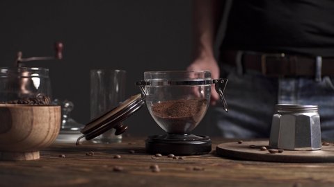 Preparation of delicious black coffee Italian moka. Geyser coffee maker on a wooden table on a dark background
