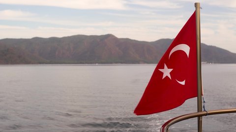 Close-up view 4k video footage of red flag of Turkey country blown by wind on sailing yacht in scenic landscape of mountainous Marmaris
