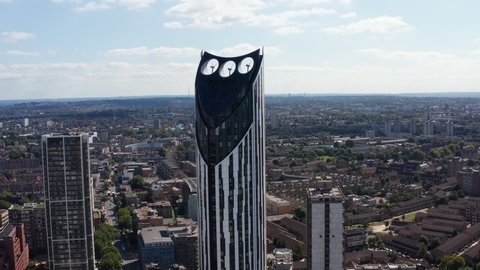 Fly around tall building with wind turbines on top as source of sustainable energy. Strata skyscraper towering above city. London, UK