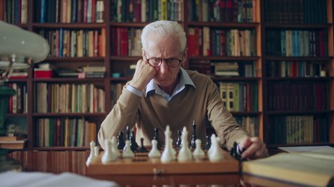 Serious grandmaster thinking over chess composition, sitting in library, hobby