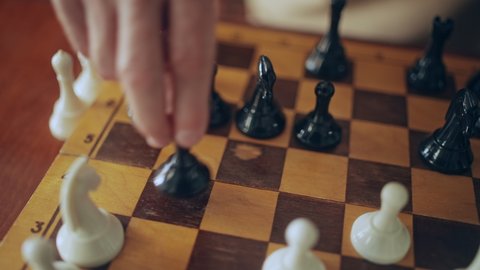 Hand of senior male making chess move on wooden board, pawn capture, hobby