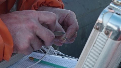 Hydrologist prepairs equipment for measurements of flow speed in river in Yamal peninsula. Scientists examining water system.