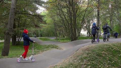 Moscow, Russia - OCTOBER 10, 2021:
Children are  riding by Kick Scooters and bicycles on the Pump Track.