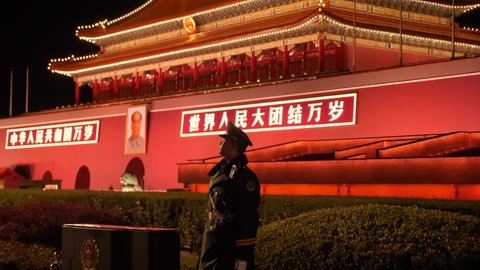 Beijing, China - Nov 1 21: Security police officer standing at Tiananmen gate to Forbidden City in Beijing China. Portrait of Mao Zedong. Tiananmen Square Sightseeing Night.