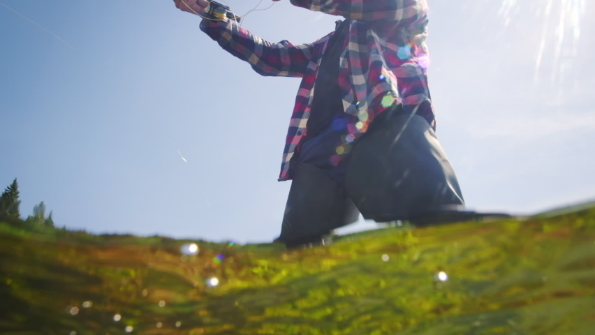 Fly fishing. Splitted underwater footage of the fan fishing on the river on fly. Male caucasian angler fishing and casting the fly on a rapid river