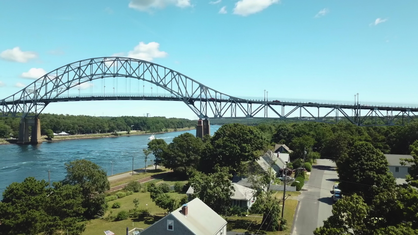 The beautiful Bourne Steel Bridge in Bourne, Massachusetts. A beautiful sunny day on the Cape Cod Canal. Cars are driving on the bridge. Shooting from a drone from a bird