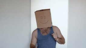A man with a box on his head is dancing, there are noises in the video. Freak with a smile.