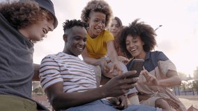 Happy smiling teenage friends laughing outside at something in smartphone or mobile phone. Young multiracial people spending time together. Friendship, communication, youth and lifestyle concept - Powered by Shutterstock - Get 15% off with code: PIKWIZARD15