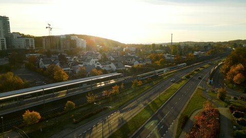 Passenger Railway train arriving at Gdynia Redlowo station early in the morning at bright Autumn sunrise aerial view, several carsing on droga Gdynska highway