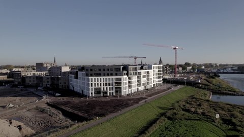 Kade Noord apartment complex at the riverbank of river IJssel revealing construction site of Kade Zuid with large red cranes in Noorderhaven neighbourhood of tower town Zutphen