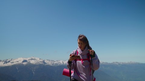 tourist woman is orienting by electronic map in mobile phone in mountains, hiking and trekking in highland at summer, modern technology for travellers