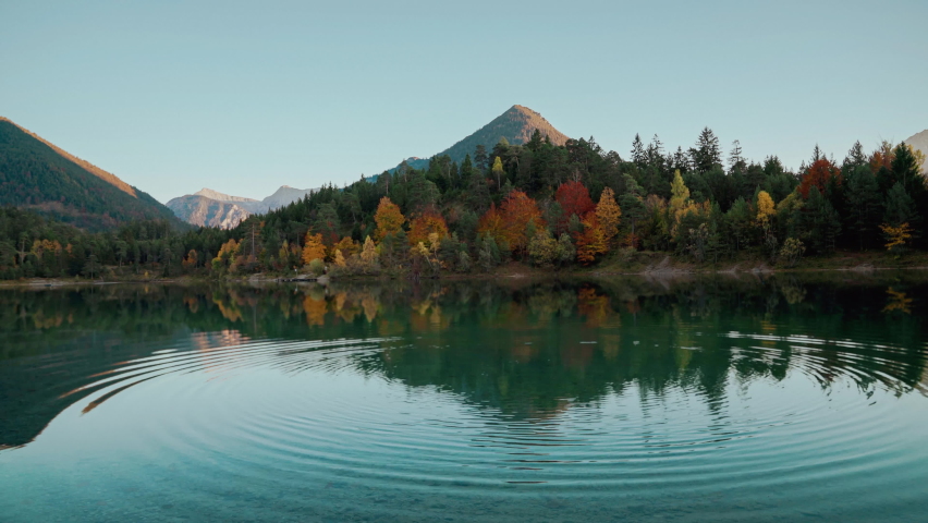 4K UHD Cinemagraph seamless video loop of a mountain lake in the Austrian alps with vibrant autumn leaves and reflection, close to Germany. The water is moving in circular waves, colorful fall trees.