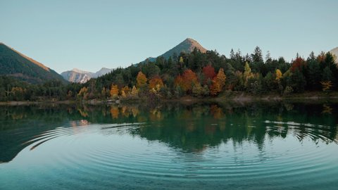 4K UHD Cinemagraph seamless video loop of a mountain lake in the Austrian alps with vibrant autumn leaves and reflection, close to Germany. The water is moving in circular waves, colorful fall trees.