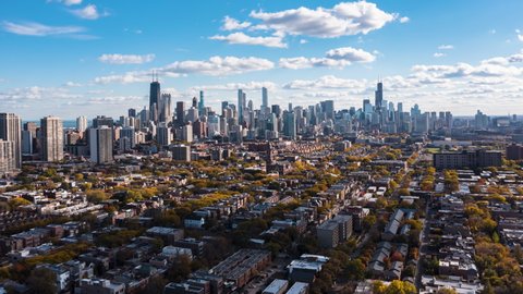 Chicago Downtown skyline during fall season with orange trees. Sunny sky with white rolling puffy clouds. Aerial Hyperlapse