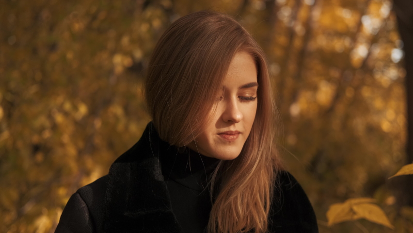Young beautiful girl covers her face from the sun. Autumn season. Sunny weather.