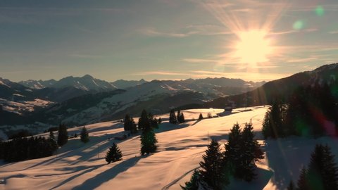 Golden Sun Light at Sunset in Mountains. Beautiful Sunny evening. Aerial view of Winter Mountains. Beautiful Winter Landscape. Flying above Snowy Alps mountains.