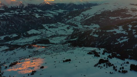 Golden Sun Light at Sunset in Mountains. Beautiful Sunny evening. Aerial view of Winter Mountains. Beautiful Winter Landscape. Flying above Snowy Alps mountains.