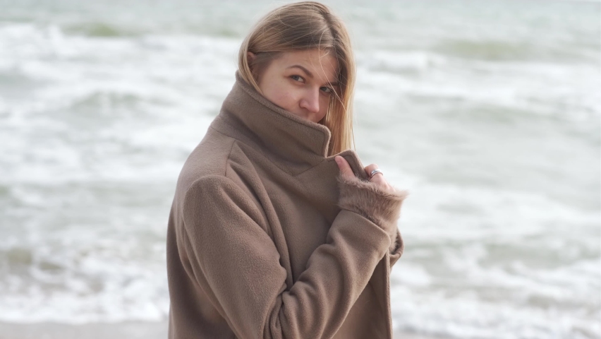 Portrait of romantic blonde woman walking on the beach in autumn sunny day