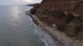 
cold autumn black sea, storm and strong waves, rocky coast with red clay and trees, video filmed from a drone