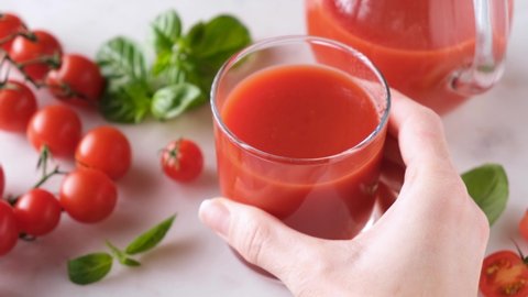 Glass of tomato juice on table. Female hand take tomato juice. Healthy food
