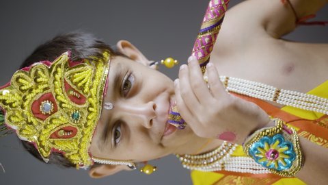 Vertical Portrait shot ofkid in Lord krishna costume playing flute during shri krishna Janmashtami
