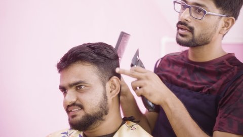Barber busy in doing haircut to customer by interacting and asking about his suggestions about hair style - concept happy customer service at saloon and communication skills at workplace.