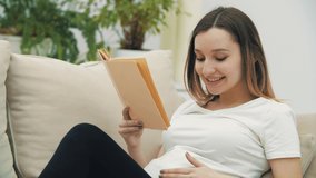 4k video of pregnant woman on the sofa reading a book.