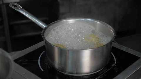 professional kitchen of the restaurant. saucepan with boiling water on the stove. potatoes are boiled in a saucepan, steam is on