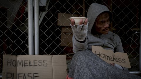 Homeless man with dirty clothes holding a cup and getting some money from kind peoples. 4K	
