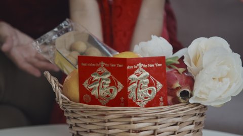 Close up shot of unrecognizable family putting pomelos and Chinese New Year postcards into basket