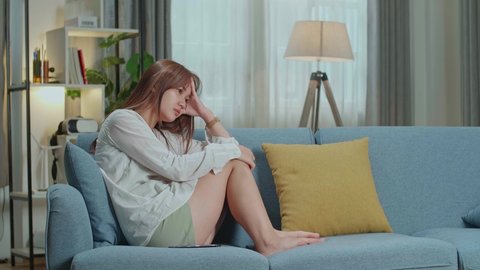 Unhappy Lonely Depressed Young Asian Woman At Home, She Is Sitting On The Couch, Depression Concept
