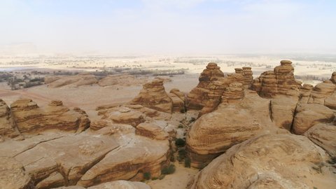Aerial Moving Forward And Descending Into Eroded Desert Rock Formation With Hazy Skies And Arid Terrain - Arabian Desert, Saudi Arabia