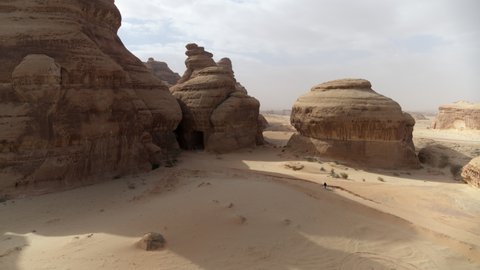 Panning Shot Of Person Walking Towards Rock Built Structures During Vacation - AlUla, Saudi Arabia