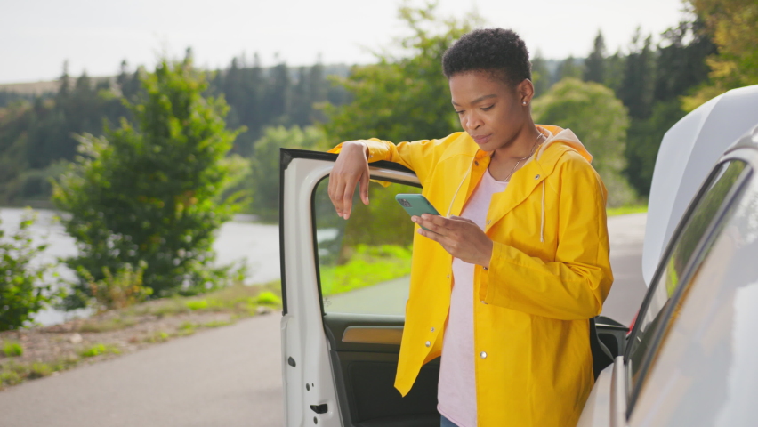 Car breakdown. Young african woman standing on road, contacting auto service online and receiving solution help waiting on road and celebrating victory. Royalty-Free Stock Footage #1081799279