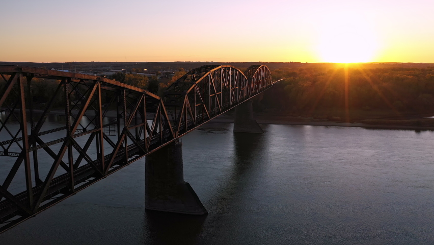 Flying along historic old railroad bridge in North Dakota at sunset over the Missouri River near Bismarck.