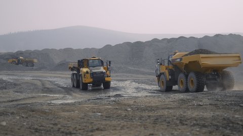 Yagodnoye, Russia, August 25, 2021. Komatsu HM400 dump trucks drive through a gold mining site.