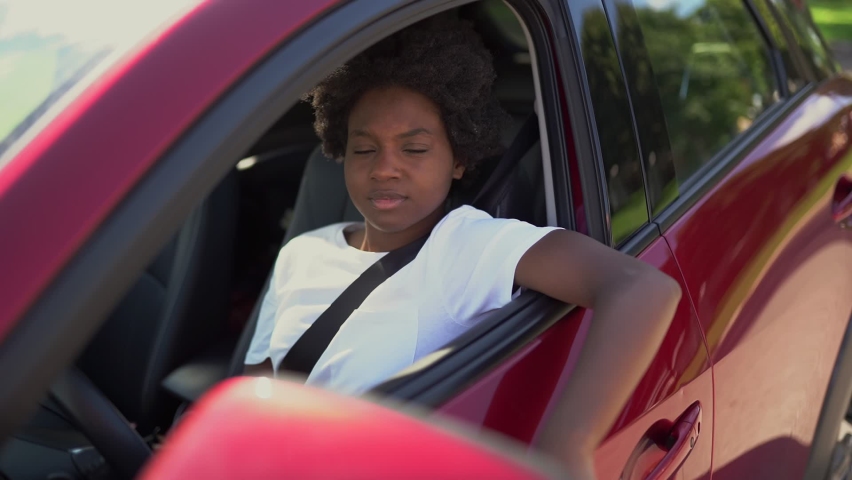 A Young black woman sit on is first red car