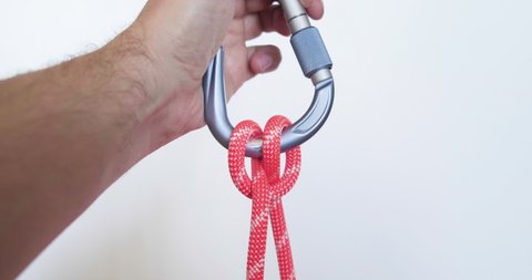 Tying a clove hitch on a carabiner using a red colored rope. This clove hitch knot used in climbing is called Mastwurf in German and Noeud de cabestan in French.