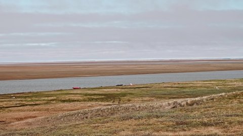 View of landswell of Yamal peninsula and Kara sea. Boats of hydrologists are on the shore. Cloudy afternoon