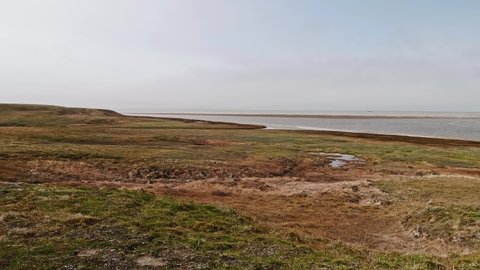 Panoramic view of landswell of Yamal peninsula and Kara sea. Flock of geese flying in the sky over water.