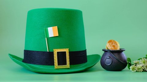 Patrick Day.Green leprechaun hat, flag of Ireland, bowler hat with gold coins, bunch of clovers on a green background. Saint Patrick holiday. St patricks day background. 4k footage