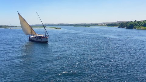 Aerial drone shot of a sailing ship navigating through Nile river as a tourist cruise. 4K footage of boat navigating and touring in Egypt.