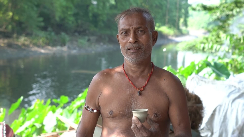 Portrait head shot of a senior potter artist standing with his hand made Kulhar or Bhand made by clay near a river at Kolkata, West Bengal.
