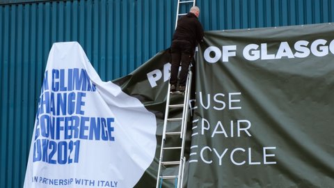 GLASGOW, NOV 2021 - Worker attempts to fix a large COP 26 banner blown away, a metaphor for the likely outcome of the Conference, as world leaders fail to make timely commitments to carbon neutrality