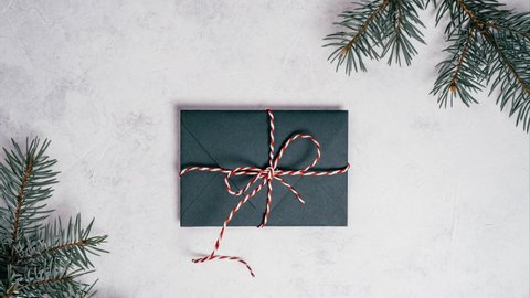 Stop motion video of green opening envelope on white background with branches of Christmas tree. Kraft paper card is taken out of new year envelope and opened. Copy space. Top view
