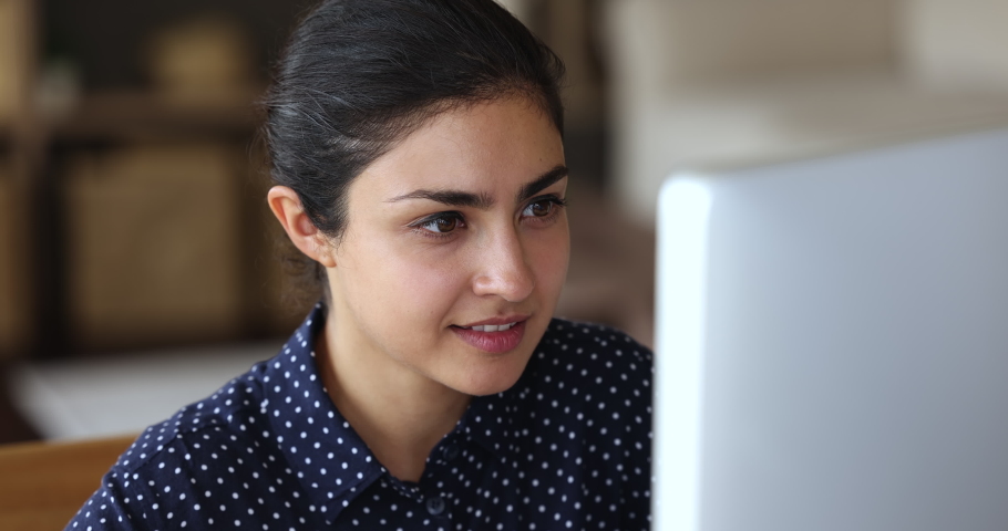 Smiling inspired young Indian female freelancer sit by computer enjoy working process create startup develop software code. Happy millennial lady journalist full of good new ideas write article on pc Royalty-Free Stock Footage #1081831556