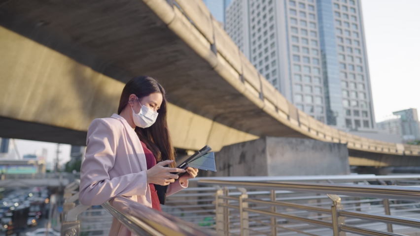 Attractive business woman leaning on metal handrail on walking bridge with hand using on a digital tablet, convenience wireless device for outside working, an online working technology innovation | Shutterstock HD Video #1081831841
